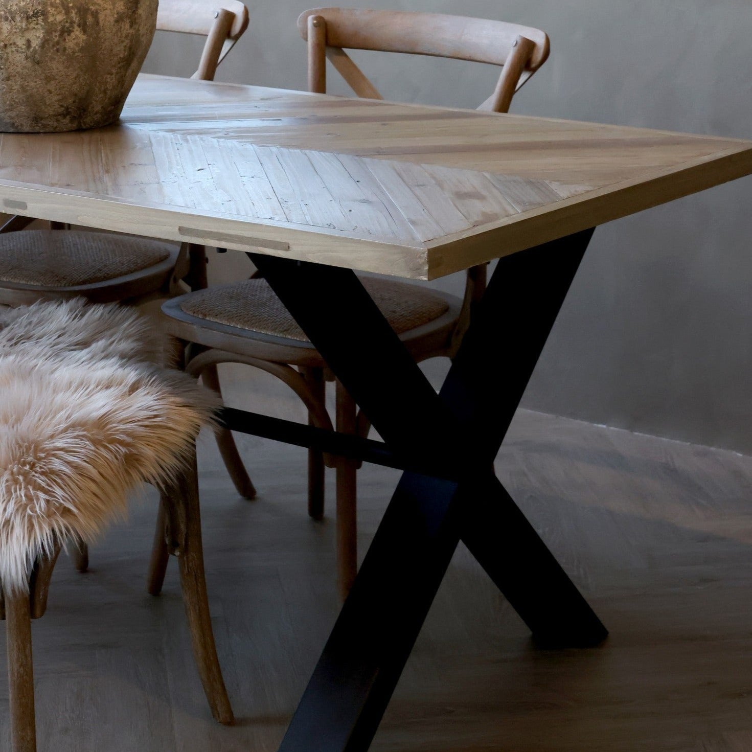 Teilansicht der Tischplatte mit Fischgrätenmuster aus Kiefer und schwarzem Eisenständer