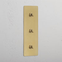 Corston-Kipphebelschalter 3x in vertikalem Dreifachrahmen – Antikes Messing