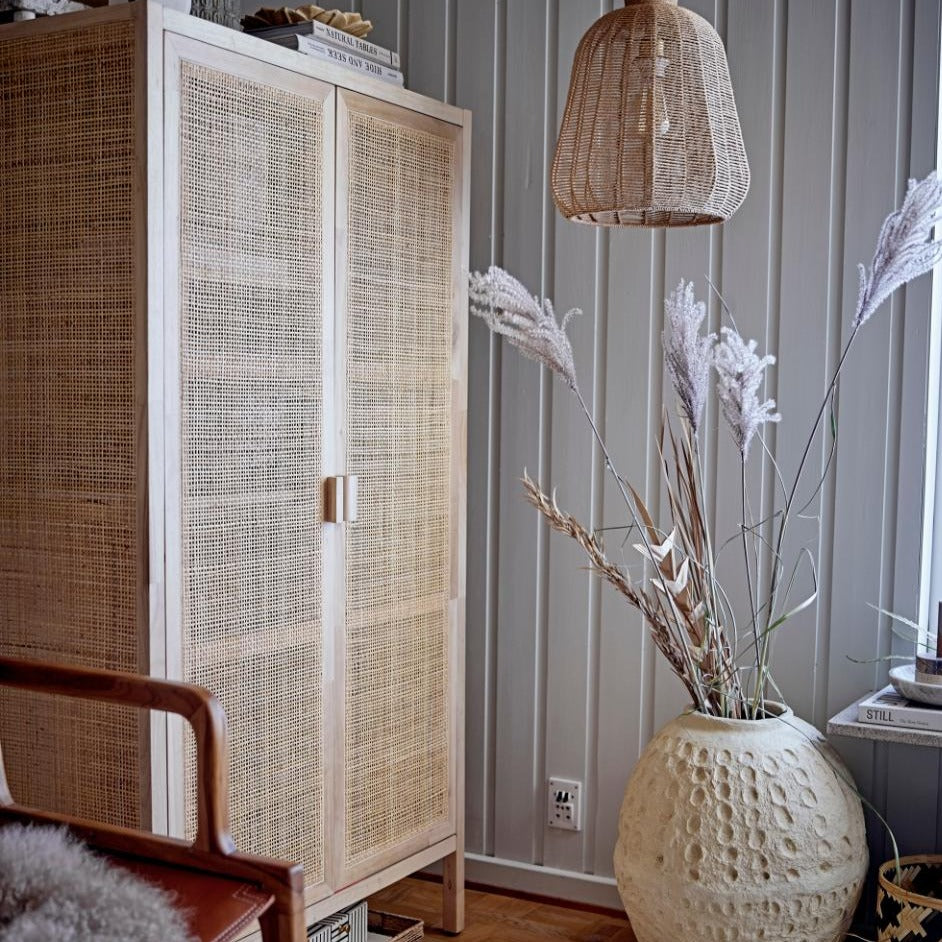 Rattan Kleiderschrank aus Gmelina-Holz in einem dekorierten Zimmer.