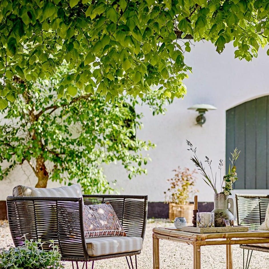 Outdoor Loungesessel aus schwarzem Metall im Garten unter einem Baum. Wetterfester Gartensessel für entspannte Stunden im Freien.