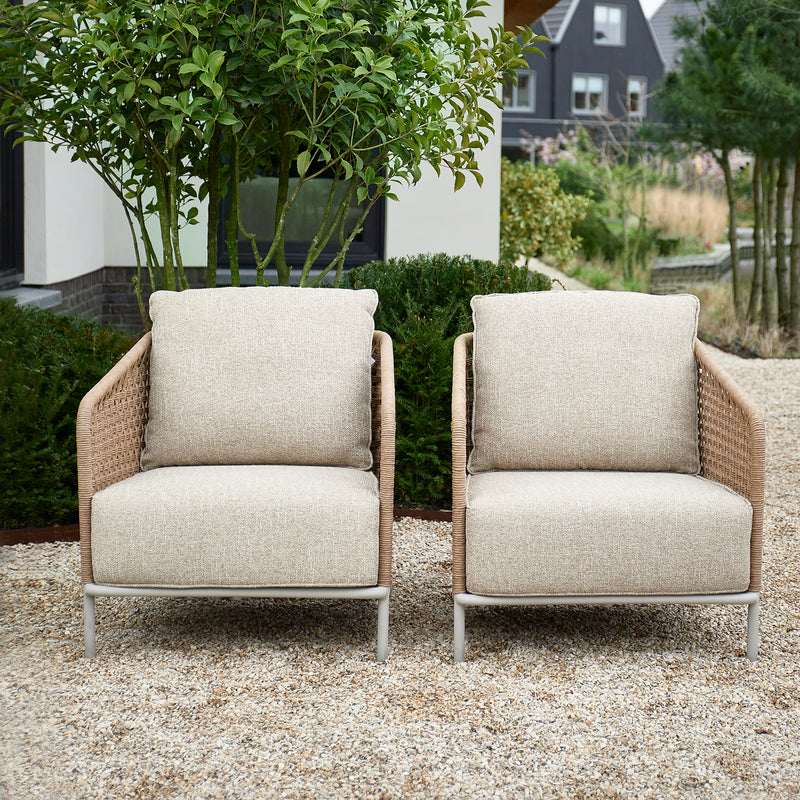 Zwei wetterfeste Outdoor-Loungesessel aus Rattan im Garten, perfekt für entspannte Stunden im Freien.